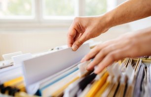 Close-up of hands searching in a file cabinet